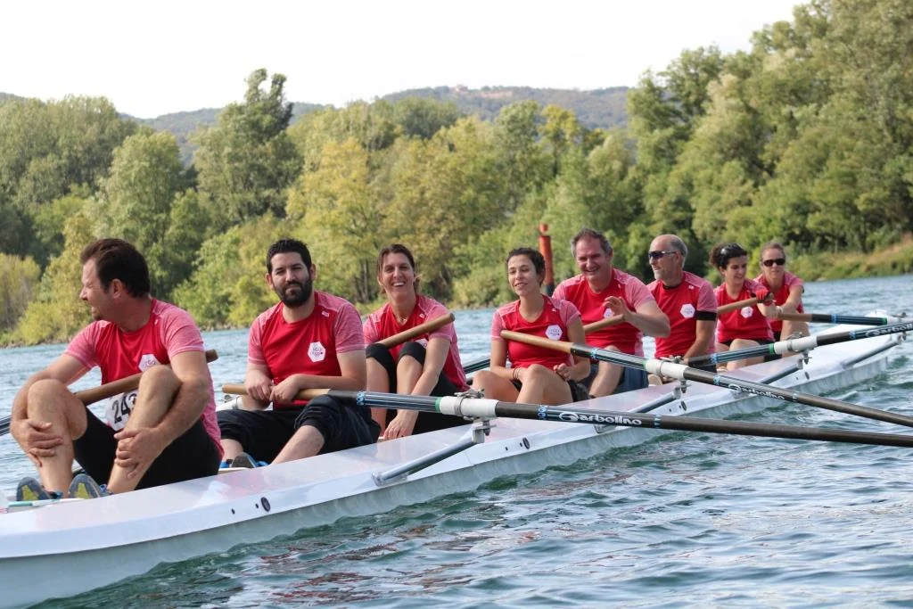 A crew in red kit shares a moment of camaraderie on the water with Esprit d'Équipe Rowing