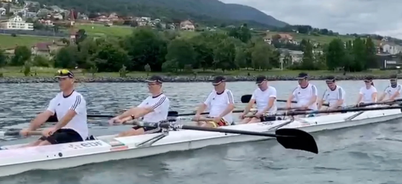 A crew of eight rowers rowing at full pace on the lake, guided by Esprit d'Équipe Rowing