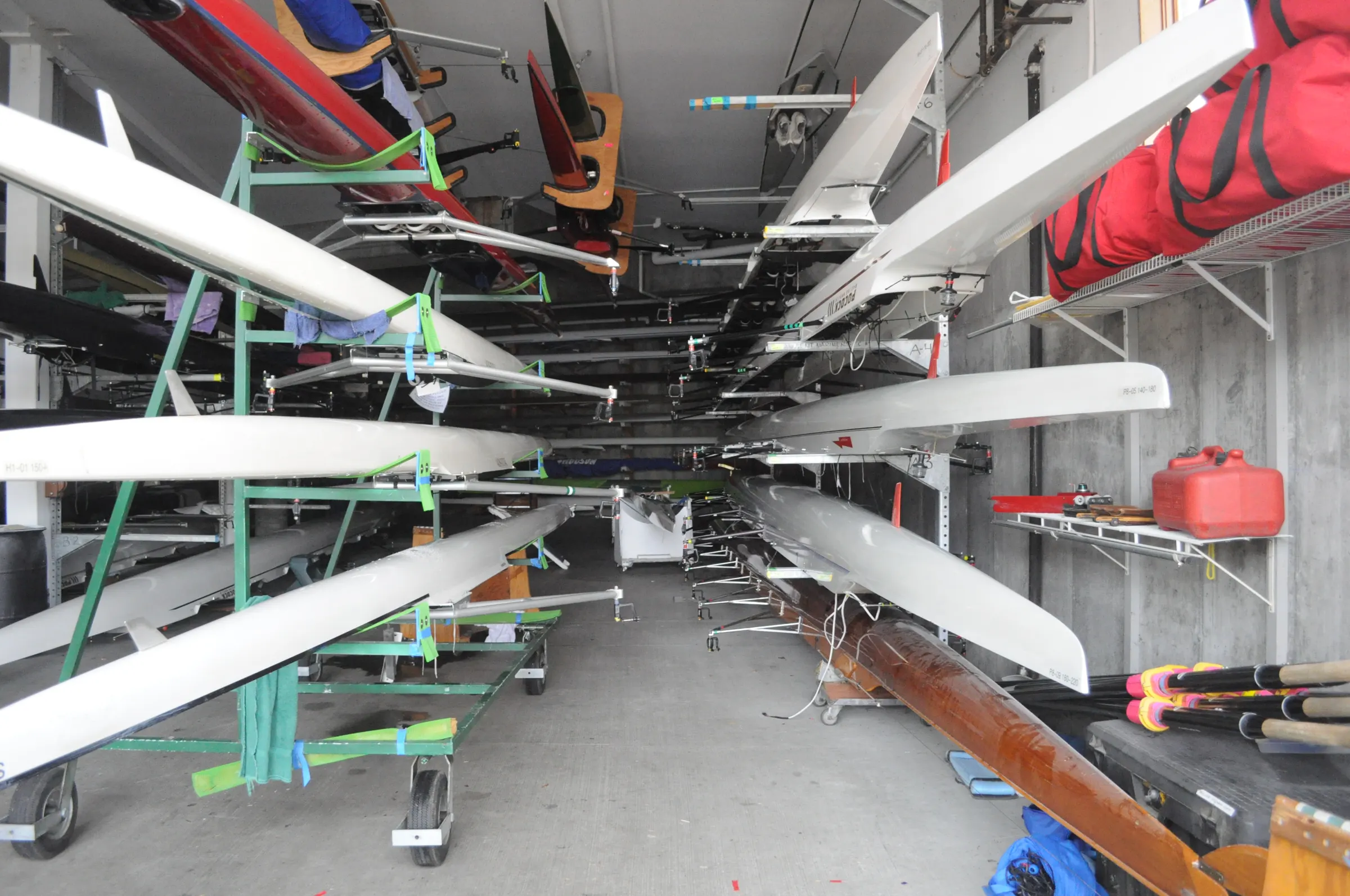 Photographie d’illustration : bateaux d’aviron rangés sur des supports dans un hangar