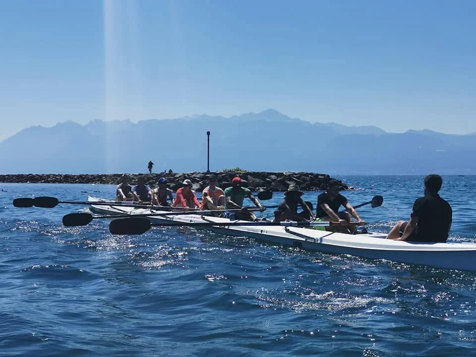 A crew rows on Lake Geneva, facing the Alps