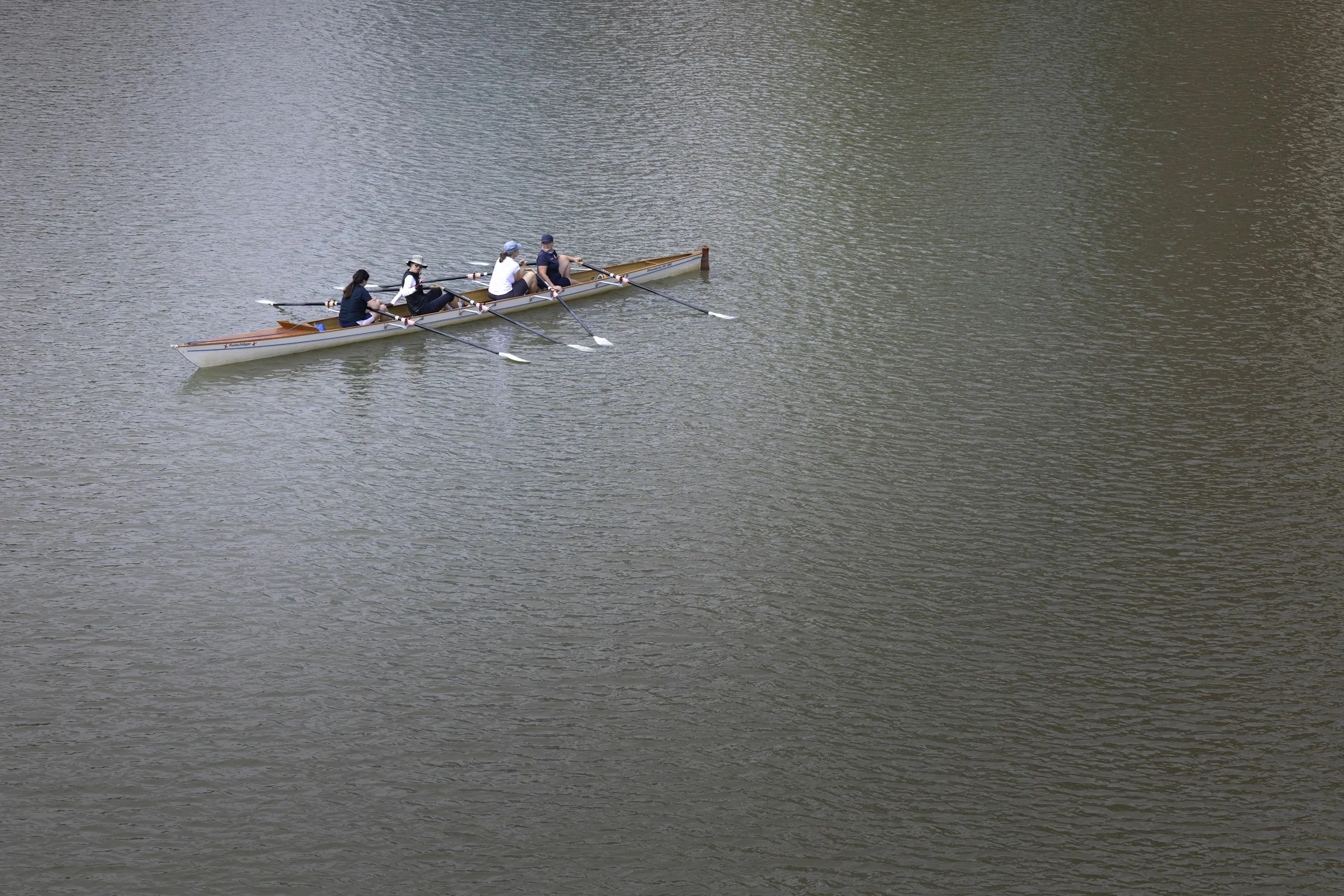 Photographie d’illustration : quatre rameuses dans un bateau d’aviron sur une eau calme